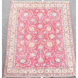 A large hand woven Persian carpet with shah abbas floral motifs throughout on a red ground, with