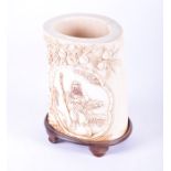 A late Qing dynasty carved ivory brush pot modelled with a lobbed cartouche depicting an elderly man