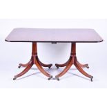 A reproduction mahogany twin pedestal dining table with two leaves, on swept legs terminating in