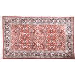 A hand woven silk Persian rug designed with central red ground decorated with extensive floral