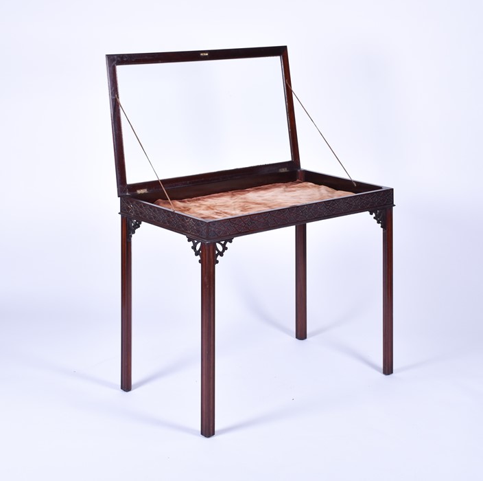 An Edwardian mahogany bijouterie table with carved frieze and glazed cover, on four shaped square