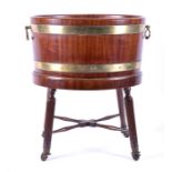 A George III mahogany oval brass bound wine cooler with twin brass carrying handles, and supported