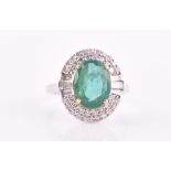An 18ct white gold, diamond, and emerald cluster ring set with a mixed oval-cut emerald of