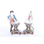 A pair of Continental Royal Dux style porcelain figural comports each modelled as a lady and