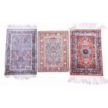 A group of three Persian rugs to include two woven with silk, each designed with foliage patterns