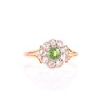 A diamond and demantoid garnet cluster ring set with a round-cut garnet, surrounded with old-cut