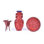 A Chinese Qing dynasty cinnabar lacquer wine vessel with carved decoration, raised on three carved