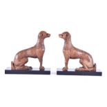 A pair of 18th century carved walnut greyhounds in a seated position, with carved textured fur