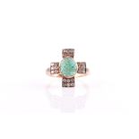 A carved emerald and diamond ring centred with an oval cabochon carved emerald, flanked to each