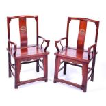 A pair of 20th century Chinese hardwood chairs with shaped crested rail backs above carved