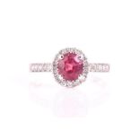 An 18ct white gold, diamond, and ruby ring set with an oval cushion-cut ruby of approximately 1.46