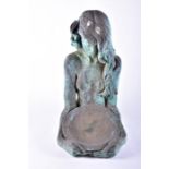 An ornamental composite material garden sculpture modelled as a woman holding a bowl, patinated