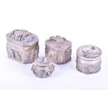 Four Eastern white metal covered boxes each with extensive relief decoration depicting figures and