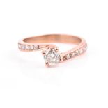 A rose gold and diamond crossover ring centred with a round brilliant-cut diamond of approximately