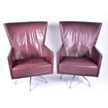 A pair of mid century design leather swivel armchairs probably Italian, with deep red leather covers