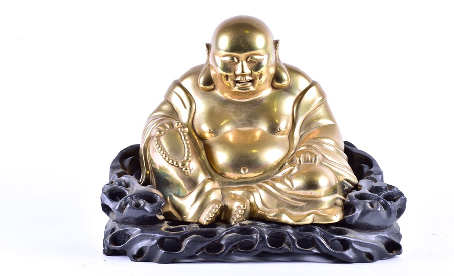 A large early 20th century Chinese brass figure of Hotei seated on a bespoke carved harwood stand,