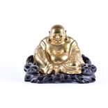 A large early 20th century Chinese brass figure of Hotei seated on a bespoke carved harwood stand,