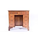 An early 20th century oak kneehole desk  with two drawers over a central cupboard door, flanked by