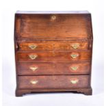 A George III oak bureau the drop flap opening to reveal a compartmentalised interior, over four