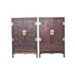 A pair of early 20th century Chinese hardwood cabinets with brass mounts, the panelled doors with