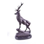 A large bronze of a red royal stag modelled as standing on a rock face, raised on a marble base,