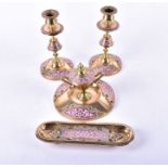 A Victorian brass and pink champlevé enamel desk set comprising a pair of candlesticks, an inkwell