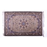 An Indian silk rug, the ivory field with a central oval medallion, with green and blue borders, with