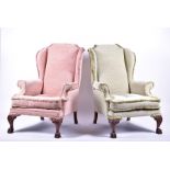 A pair of Georgian style mahogany wing armchairs in pink and green upholstery, with lion paw front
