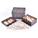 An early 20th century travelling mahjong set in bone and bamboo, 148 tiles with counters, in a two-