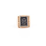 A yellow metal and hematite gents ring set with a rectangular hematite, intaglio engraved with a