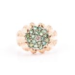 A 9ct yellow gold and emerald cluster ring the textured mount with a raised circular cluster of