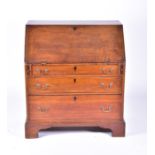 A late 18th century oak bureau the drop flap opening to reveal a central cupboard door flanked by