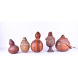 A group of African tribal vessels, modelled from gourds with carved detail, together with wicker and