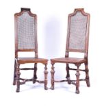 A pair of 17th century style walnut hall chairs with cane seats and backs, 125 cm high x 47 cm wide.