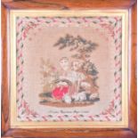 A mid 19th century needlework sampler depicting a young girl with her dog and rabbits, within a