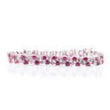 An 18ct white gold, diamond, and ruby bracelet set with oval-cut rubies alternated with diamond