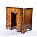 A 19th century walnut serpentine fronted kneehole desk the central door over a single cupboard door,