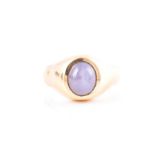 A yellow metal and star sapphire gents ring the ring embedded with an oval cabochon pale blue