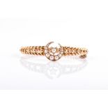 A late Victorian / early Edwardian 15ct yellow gold bangle of rope-twist form, centred with a