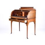 An Edwardian mahogany and inlaid roll front desk with sectioned interior over a pull-out scriber and