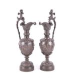 A pair of bronze Neoclassical style ewers designed with winged putti finials to the handles, vine