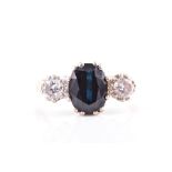 A diamond and sapphire three stone ring centred with a mixed oval-cut sapphire, measuring