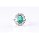 An 18ct white gold, diamond, and emerald cluster ring set with a mixed oval-cut emerald of