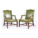 A pair of George III style mahogany Gainsborough armchairs upholstered in green leather and carved