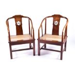 A pair of Chinese softwood horseshoe elbow chairs possibly rosewood, both with canework seats and