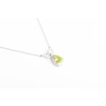 A diamond and peridot drop pendant necklace set with a mixed pear-cut peridot with a border of small