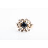 An unusual 14ct yellow gold, diamond, and sapphire ring centred with a round-cut dark blue sapphire,