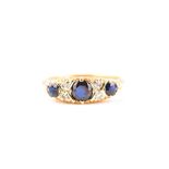 An 18ct yellow gold, diamond, and sapphire ring set with three round-cut sapphires interspersed with