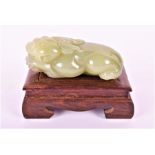 A 19th century jade figure of a fo dog the guardian figure modeled in a recumbent curled up