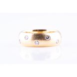 An 18ct yellow gold and diamond eternity ring the wide band with scattered diamonds, of